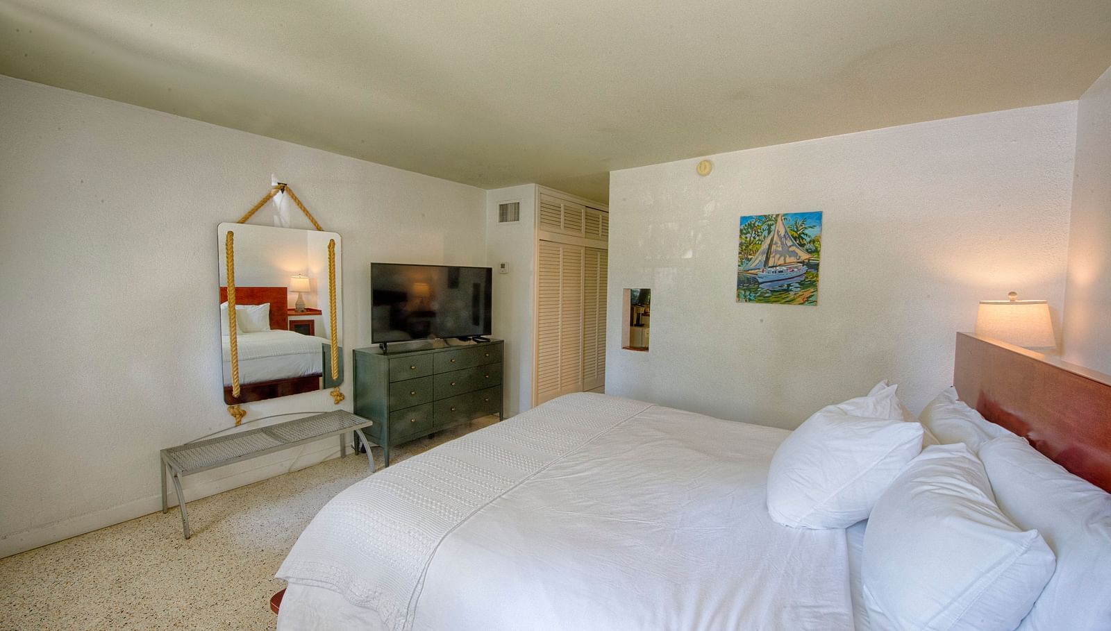 White bed in a Casa Morada suite with a mirror, open floor space, and subtle lighting.