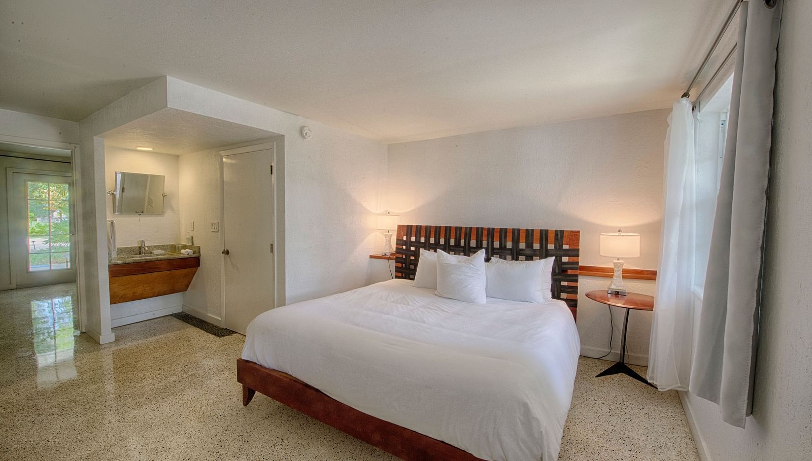 Bedroom at Casa Morada with a king bed, wooden headboard, and a sitting area near large windows.