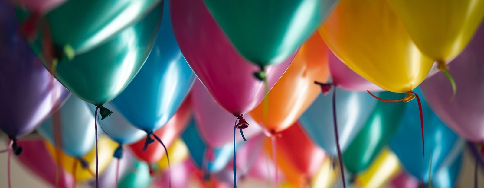 Colorful balloons tied with strings, floating in the air.