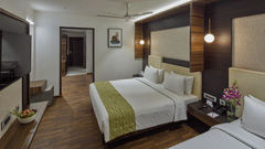 A king bed, a single bed, wall mounted tv inside the suite at Grand Continent - A Sarovar Premiere Affiliate Hotel, Hosur