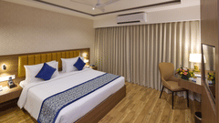 A spacious hotel room in Bengaluru featuring a king size bed, an AC, a work desk and warm accent lighting - Grand Continent, Brookefield