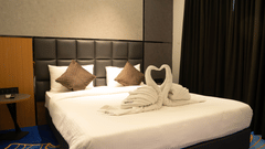Comfortable bedroom at Magnus Lxia Premier, Kalyani Nagar with plush bedding, elegant décor, and towel art on the bed.