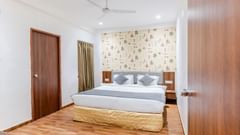 Suite at Pride Elite Wellness Resort Becharaji, Gujarat featuring a plush bed on wooden furnished floor with two nightstands on both sides