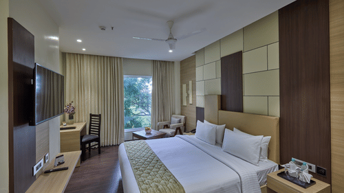 A king bed with side tables inside the deluxe room at Grand Continent - A Sarovar Premiere Affiliate Hotel, Hosur