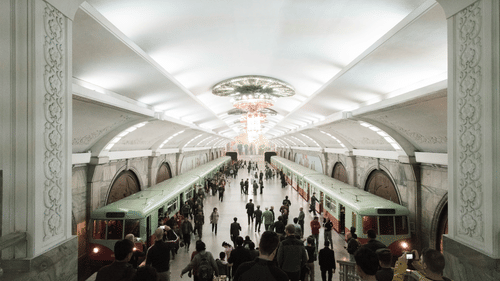 Two trains on different tracks with people thronging towards them inside a station.