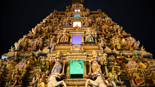 an old south indian style temple with lots of horses and other idols constructed on the exterior