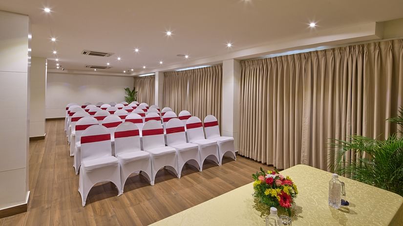 An image of a theatre style seating arrangement in our banquet hall with chairs covered in white cloth and red ribbons tied around the backrests - Grand Continent, Brookefield