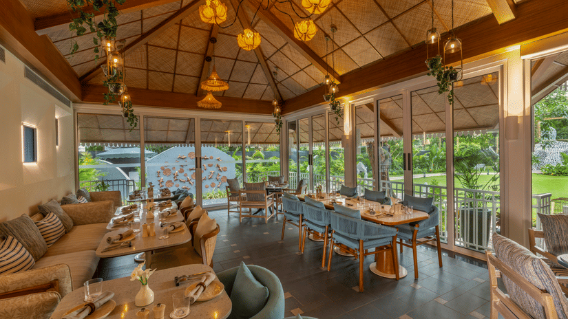 Bright and airy restaurant with wooden interiors, large windows, and scenic outdoor views.
