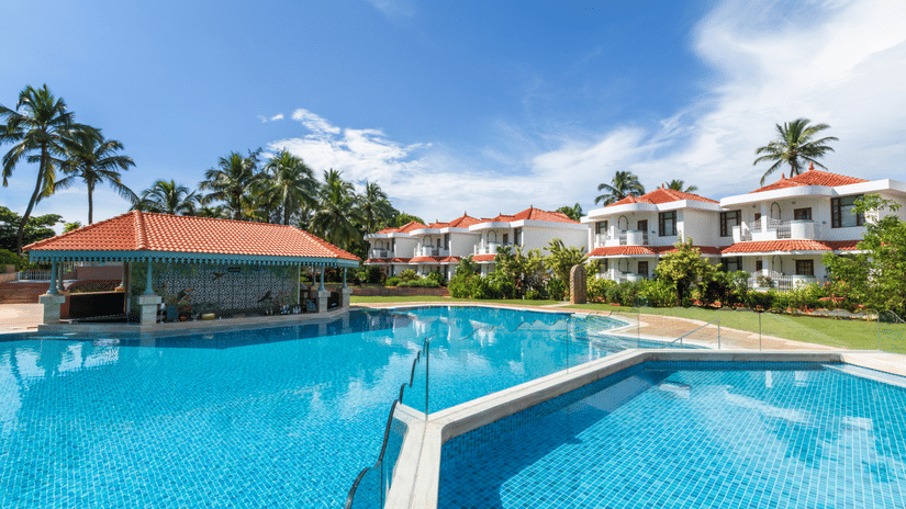 Spacious pool area with clear blue water and resort buildings in the background.