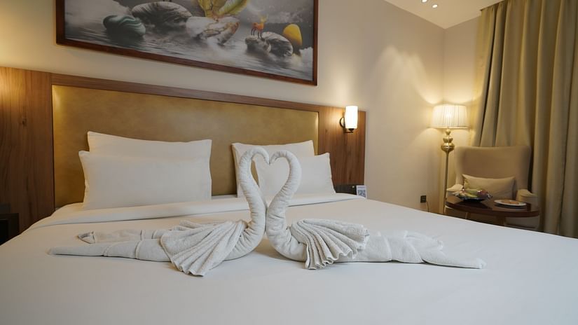 Image displaying a king bed on which the towels are made into two swans