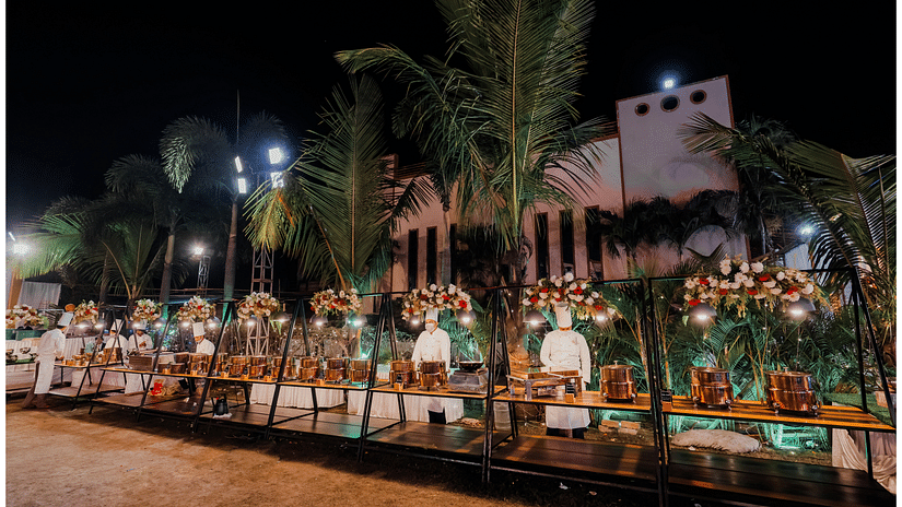 The servers stand behind the buffet, overseeing the spread during a special occasion. - Wedlock Greens Hotel Resorts Dhanbad
