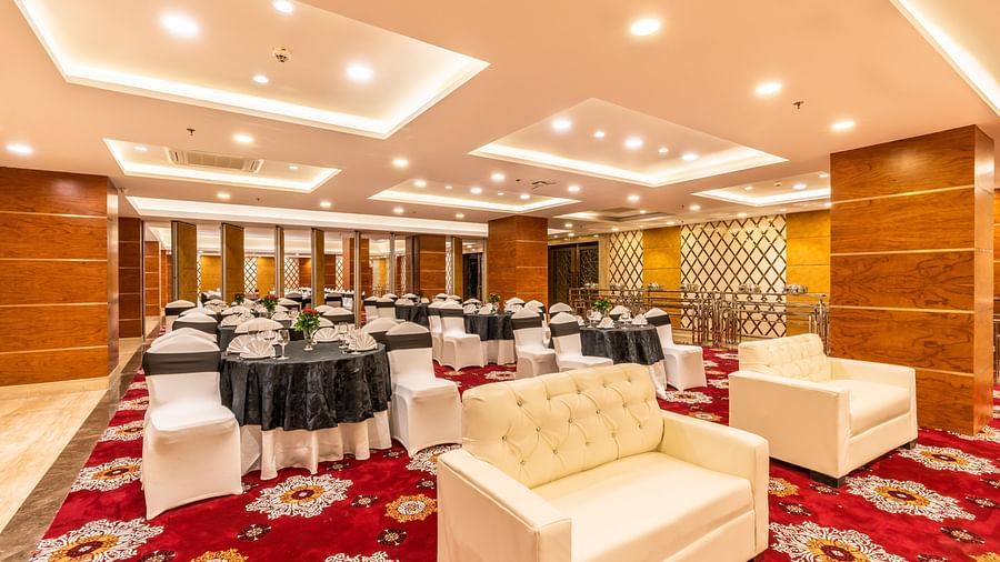 The Emerald Hall in Kurukshetra featuring a couple of sofas arranged in front of tables and chairs 
