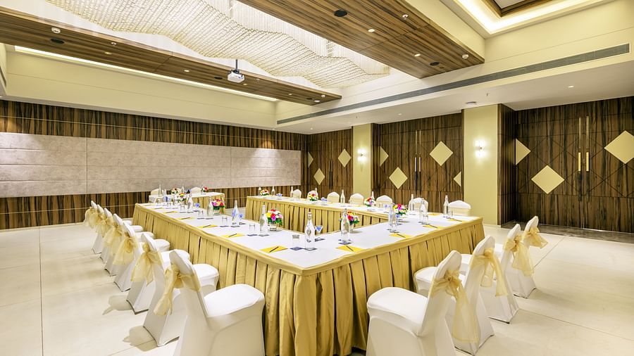 Golden Tulip, Candolim, Goa's banquet space, featuring a table setup with a gold tablecloth and plush white chairs.