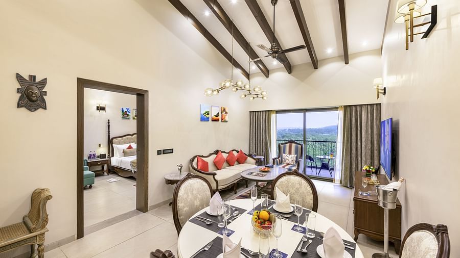 a top angle shot of a suite in candolim featuring a dining table, a balcony with verdant views, a love seat with a coffee table and a door that opens to the bedroom - Golden Tulip, Candolim, Goa