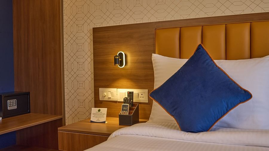 A close view of the bed in our hotel room, styled with a blue cover and an elegant bedside lamp - Grand Continent, Brookefield