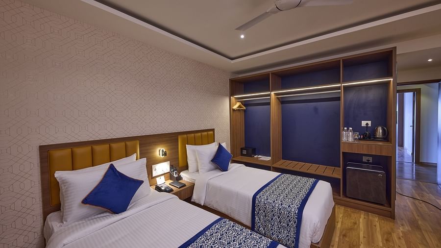 A hotel room in Bangalore with Twin beds with blue accent pillows and cosy lighting - Grand Continent, Brookefield