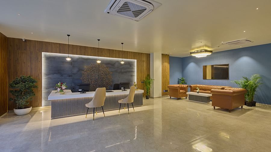 An image of hotel lobby with a reception desk and a sitting area filled with orange couches