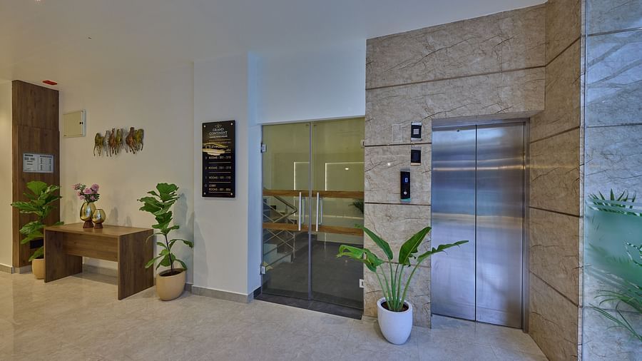 Another angle of an elevator in our hotel with a wall-mounted signboard beside the lift indicating the destinations of each floor and a small wooden table with a vase filled with flowers
