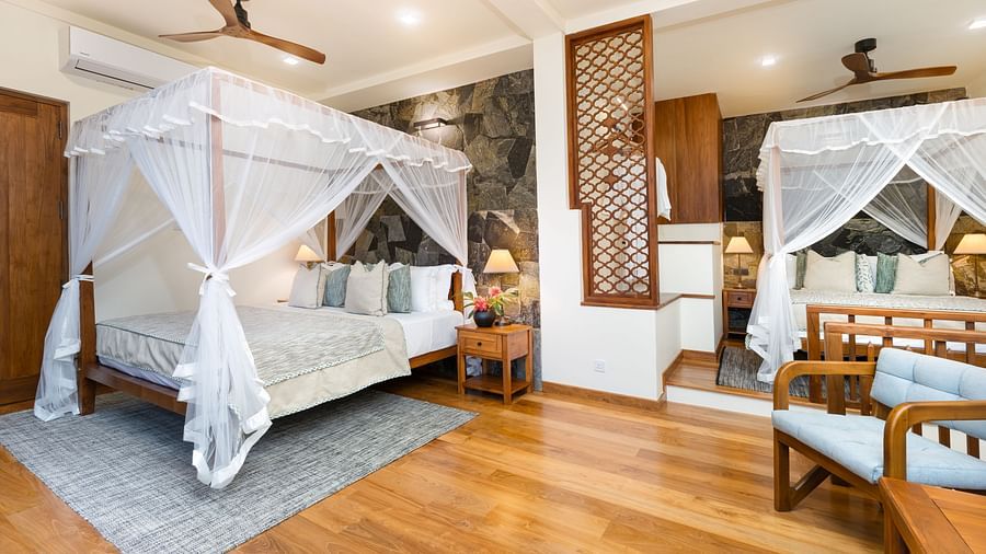 A stylish bedroom featuring a wooden canopy bed, comfortable seating, and warm wooden flooring - Family Suite Garden view at Heavensa Villas and Suites by the Clarks, Galle