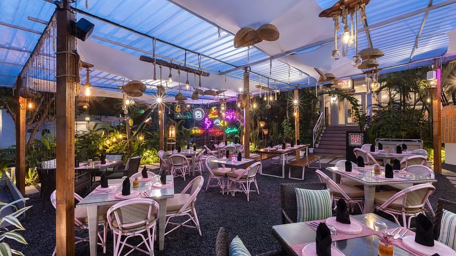 Evening view of a covered outdoor dining area with warm lighting and garden ambience.