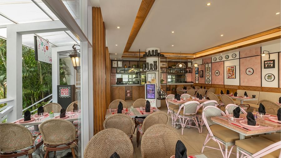 Cosy restaurant setting with wicker chairs, elegant table settings, and artistic decor.