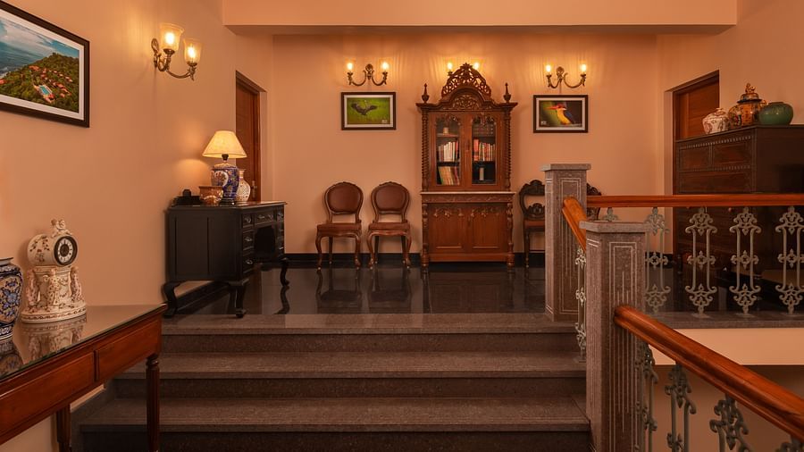A staircase leading to the next floor that features vintage chairs, a vintage cupboard, paintings mounted on walls - Highland Sarovar Portico, Sindhudurg