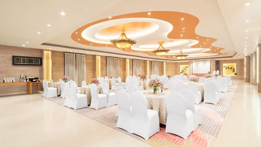 A spacious banquet hall with elegant white tablecloths and chairs, ready for a special event.