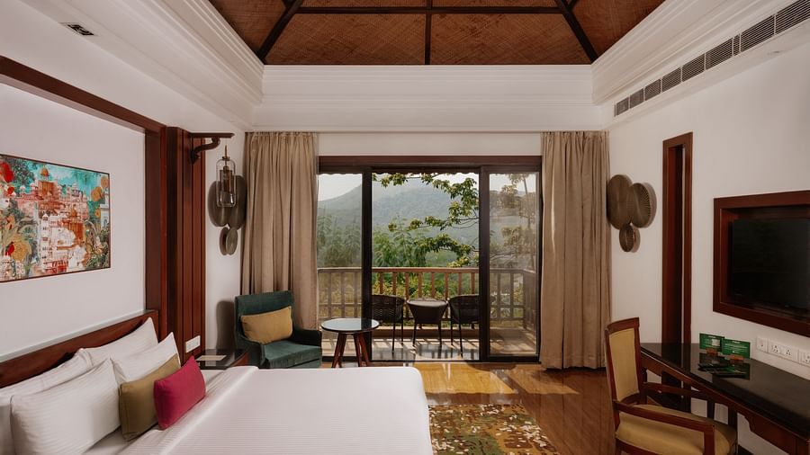 Side view of the Luxury Villa bedroom at The Ananta, Udaipur, featuring a spacious balcony with scenic views, and a flat-screen TV.