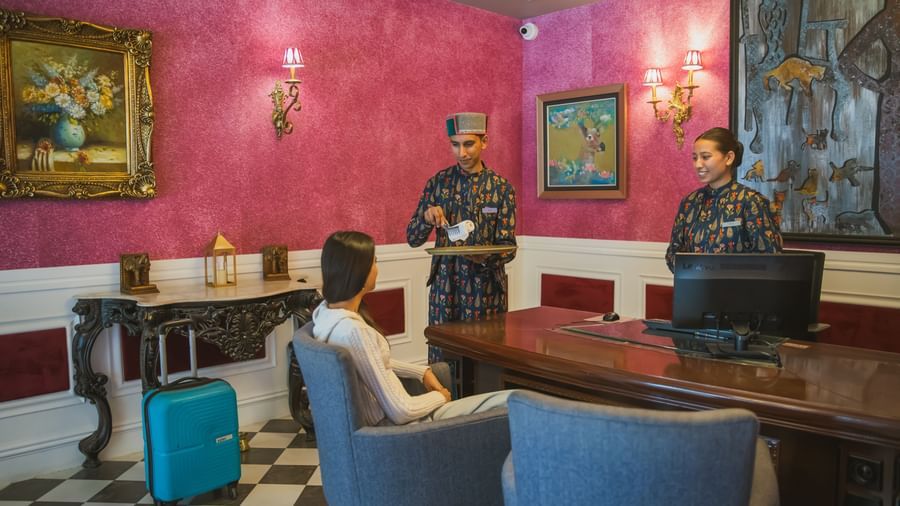 Elegant sitting area inside a luxury suite with vibrant red walls, classic art, and blue armchairs.