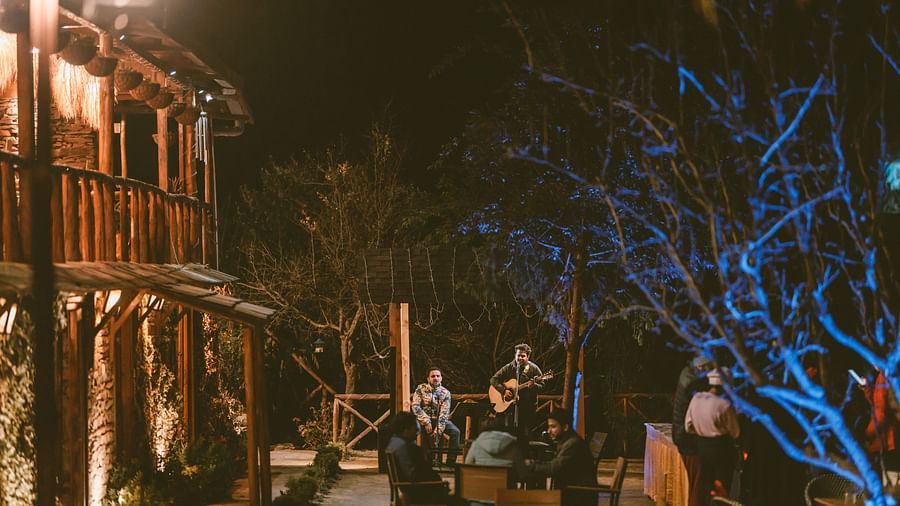  A lively outdoor gathering with people seated around a musician playing a guitar - The Manor Luxury Hotel, Shimla