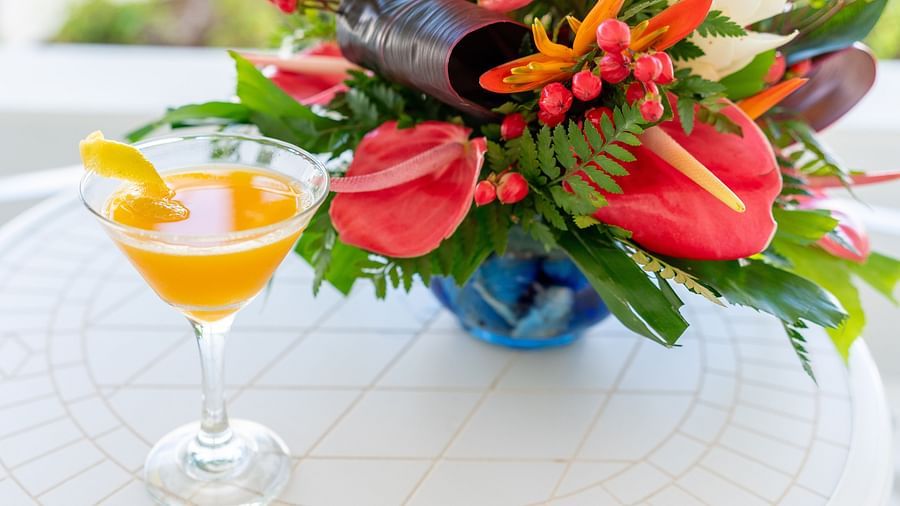 The Soco House - a drink kept on a table beside a bouquet of flowers
