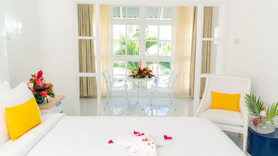 Soco House - view of a bed with yellow pillows and rose petals