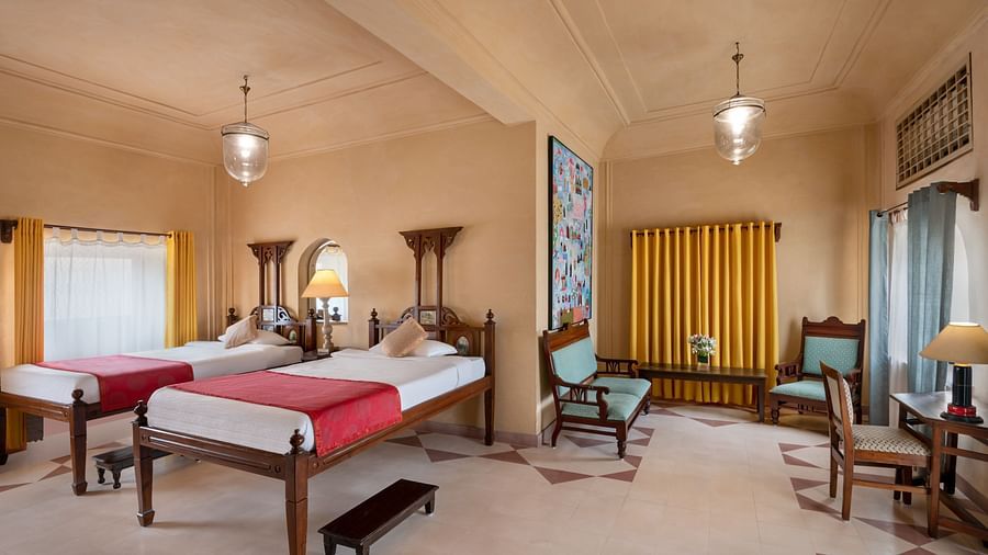 A bedroom with two beds, two chairs, and two lamps in Tijara Fort-Palace - 19th Century, Alwar.