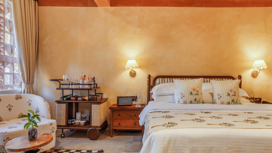 Spacious bedroom at Unseen Boutique Hotel with dresser, television, and natural light through framed windows.