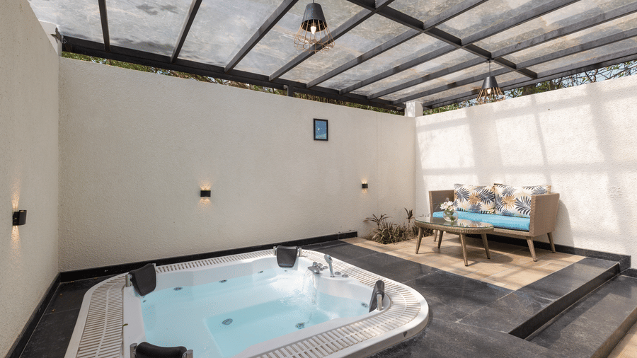 Jungle Spring Villa Private Hot Tub bathroom with a large, rectangular jacuzzi tub under a glass roof at The Golden Tusk, Jim Corbett