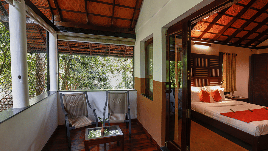 Two chairs and a coffee table in a balcony that is attached to a room | Vythiri Resort. Wayanad