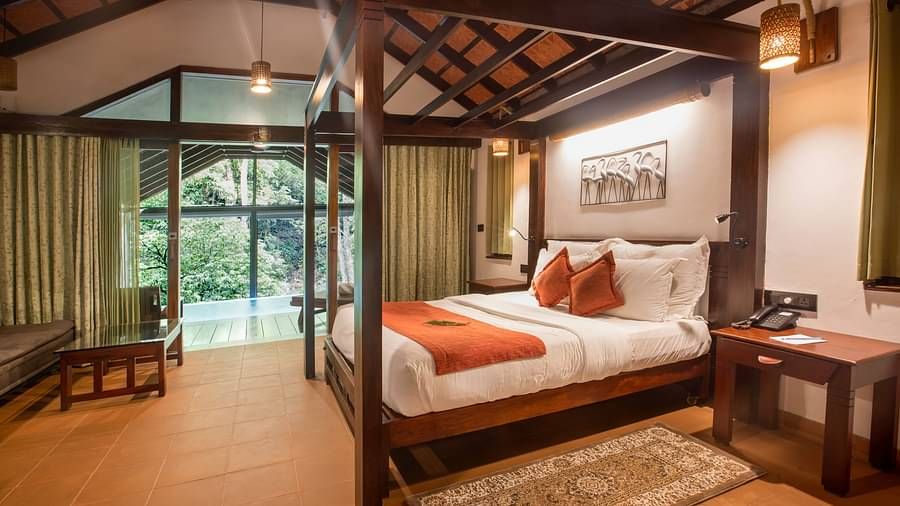A full view of a bed in a room that has forest views | Vythiri Resort. Wayanad