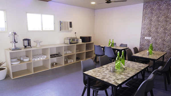 Dining area of Lime Tree Hotel, Pulkit featuring multiple tables, chairs, and a shelving unit.