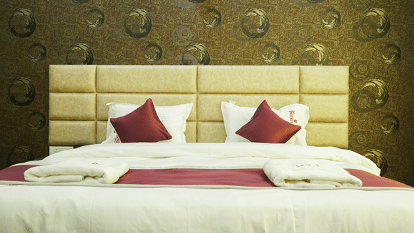 Bedroom of Lime Tree Hotel, Pulkit featuring a textured beige headboard and maroon bedding.