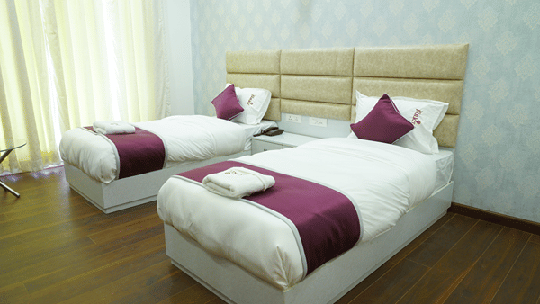 Bedroom of Lime Tree Hotel, Pulkit featuring twin beds, a beige headboard, and maroon cushions.