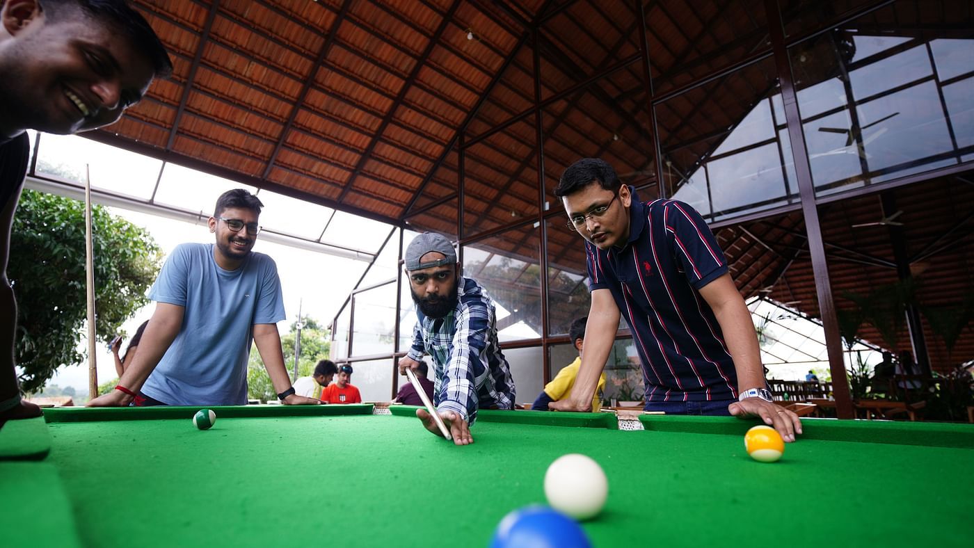 A group of people focused on snookerl with one person making the shot at Ravishing Retreat