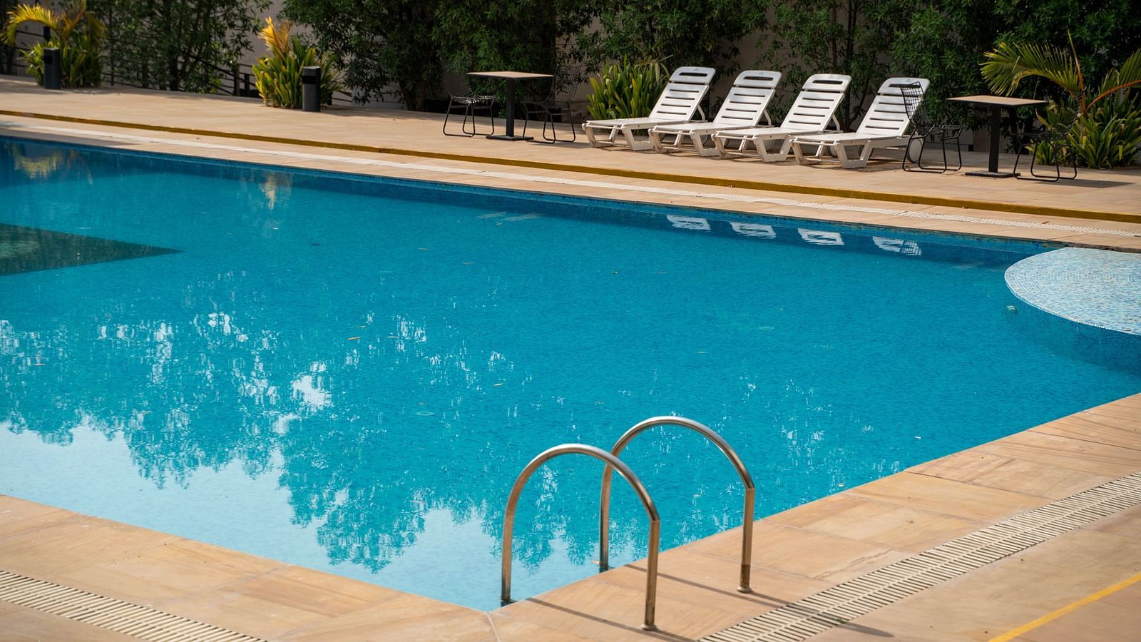 Outdoor pool with sun loungers and seating tables at the Bamboo Saa Mulberry Resort in Pushkar.
