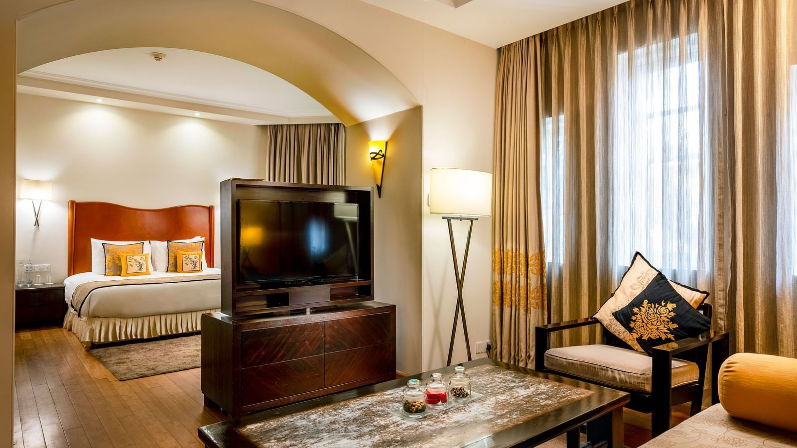 a double bed, with a tv opposite it and a living room as well inside Deluxe Suite - Caravela Beach Resort Goa