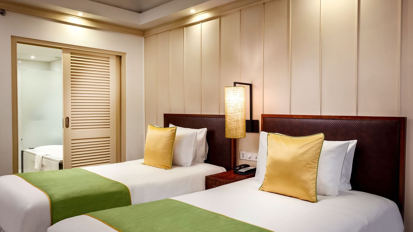 twin bed with gold pillow and a green runner on top of it - Caravela Beach Resort Goa