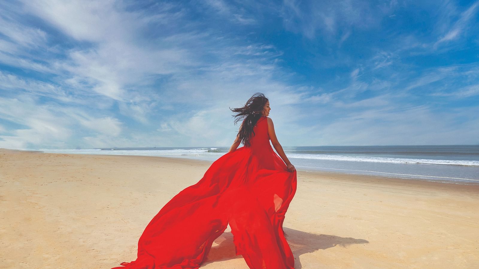 a woman with a long red dress running on the beach - Caravela Beach Resort Goa.