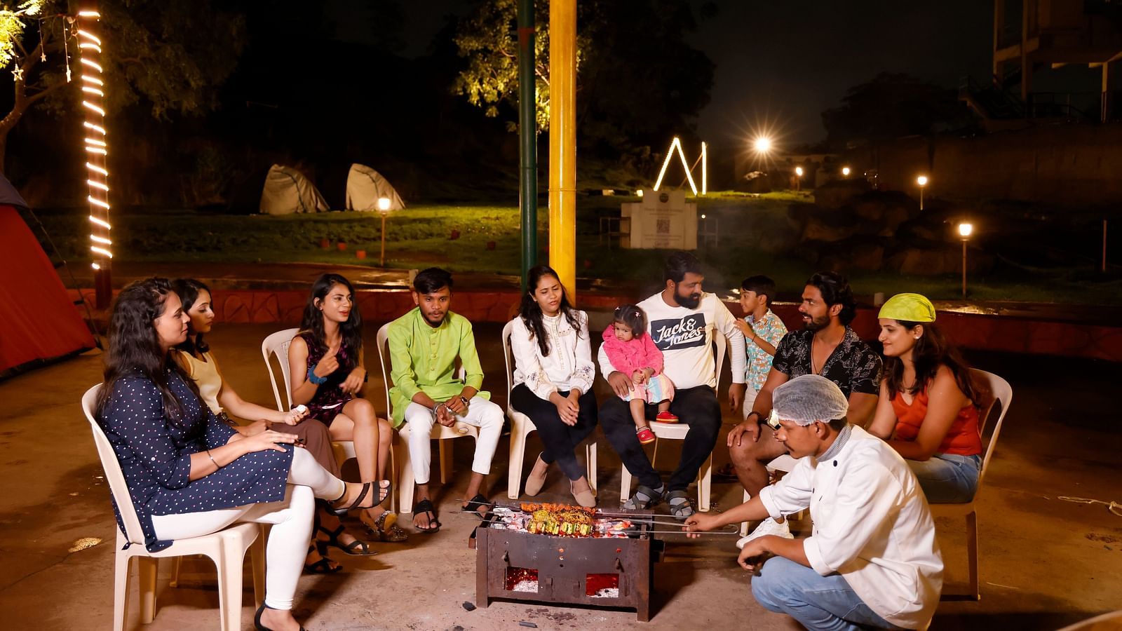 Group of friends enjoying a bonfire at a camping site in the evening | Diamond Parks, Pune