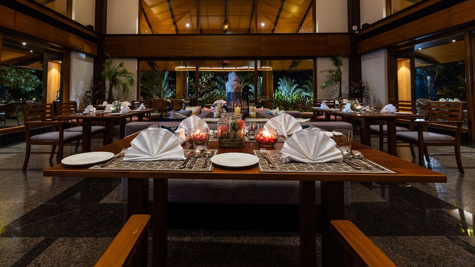 Seating arrangement inside the Restaurant with cutlery on the table in view - Gamyam Resort