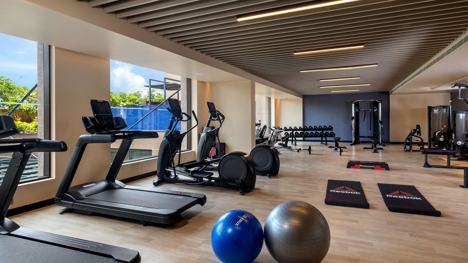 A modern hotel gym, equipped with various exercise machines and weights - Grand Madurai by GRT Hotels