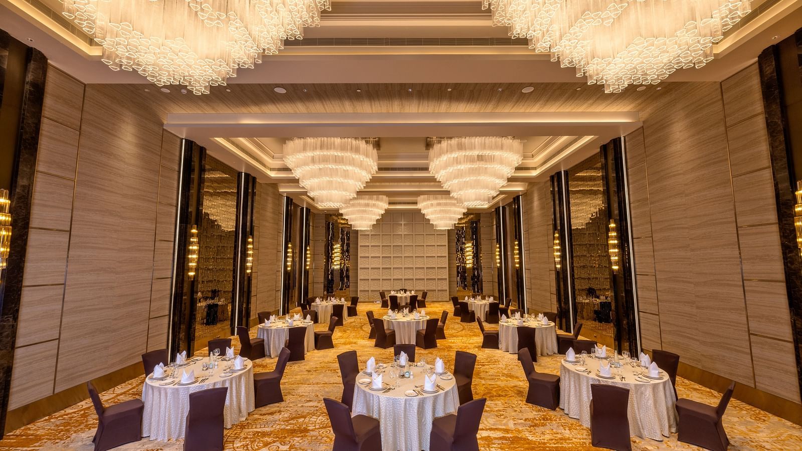 Grand banquet hall setup for a formal event with circular tables and chandeliers - Grand Madurai by GRT Hotels