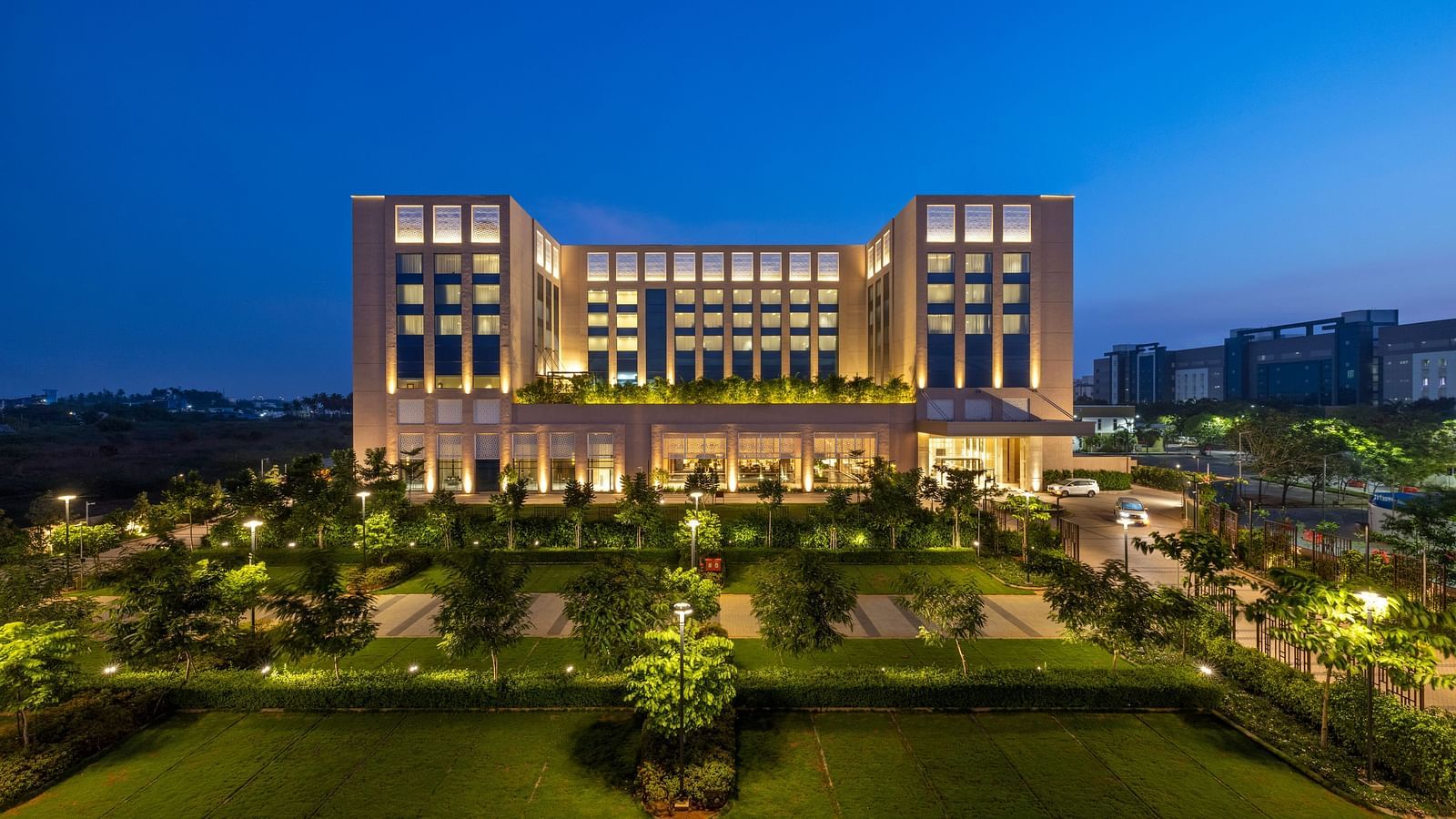 A striking twilight aerial perspective of the hotel, surrounded by manicured lawns - Grand Madurai by GRT Hotels